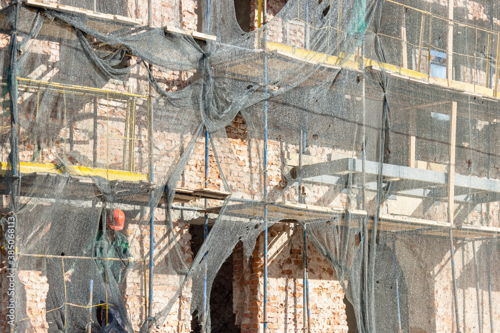 restoration of the building and the scaffolding is covered with a cloth for protection from dust and debris. the work of builders to maintain buildings in proper form.