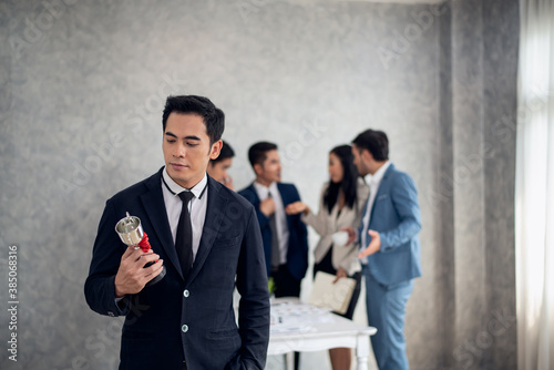 Businessman happy pride with win cup and business team jealous behind