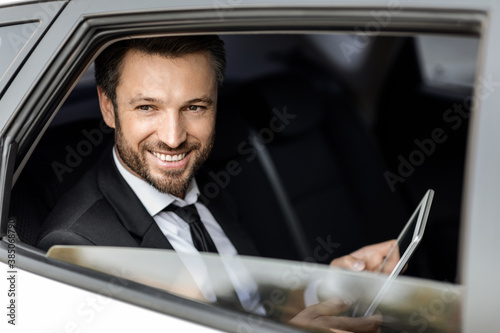 Smiling rich businessman in suit sitting in car © Prostock-studio