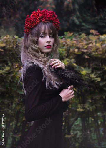 Gothic portrait of a girl in a wreath of rowan with a raven. Fall.