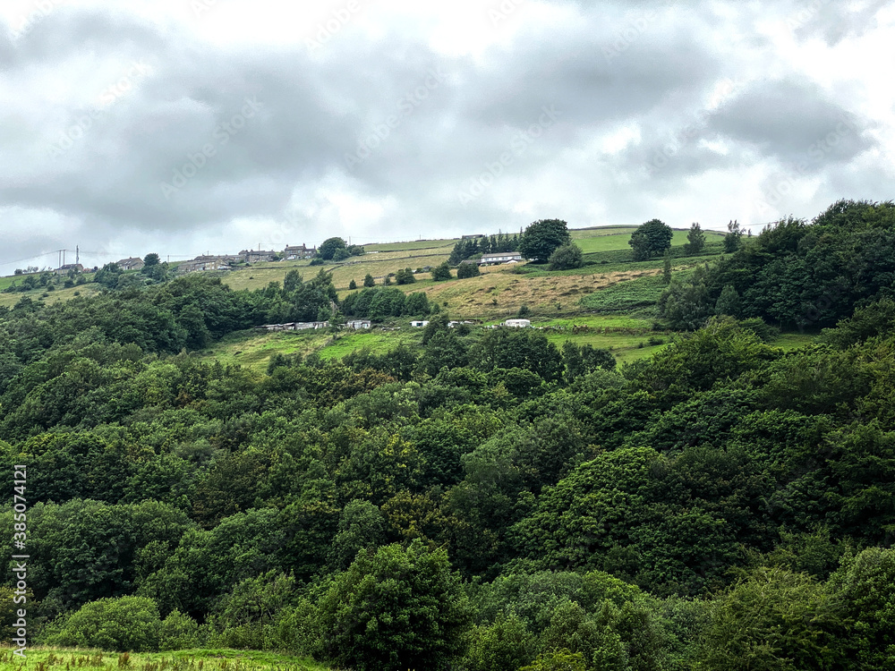 View over, a small forest with distant fields, caravans, and houses in, Slaithwaite, Huddersfield, UK