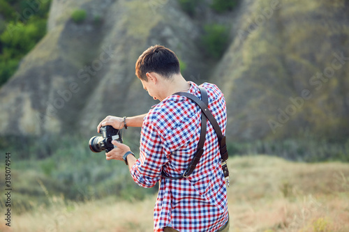 young man photpgrapher talking pictures outdoors in sunny day