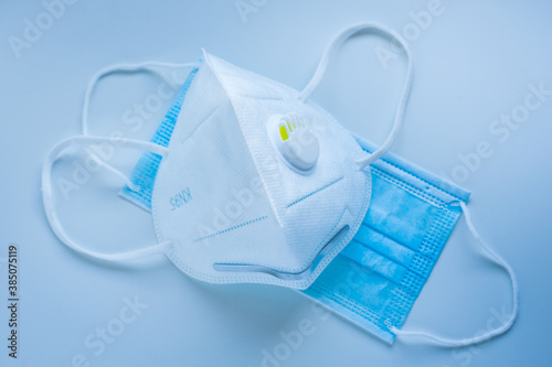 Respirator with exhalation valve and medical protective mask on a blue background