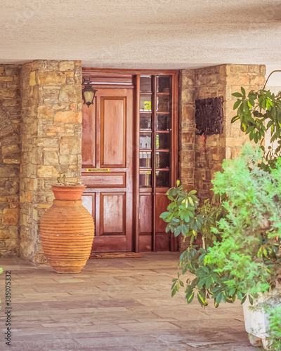 Fototapeta Naklejka Na Ścianę i Meble -  contemporary house entrance with natural wood door, stone covered wall and huge jar, Athens Greece