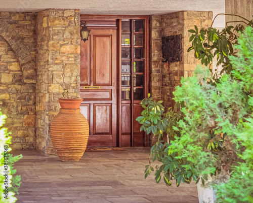 Fototapeta Naklejka Na Ścianę i Meble -  contemporary house entrance with natural wooden doors, stone covered walls and a huge jar