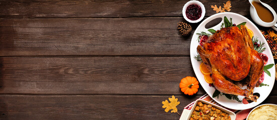 Traditional Thanksgiving turkey dinner. Overhead view side border on a dark wood banner background with copy space.