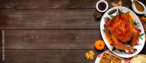 Traditional Thanksgiving turkey dinner. Overhead view side border on a dark wood banner background with copy space.