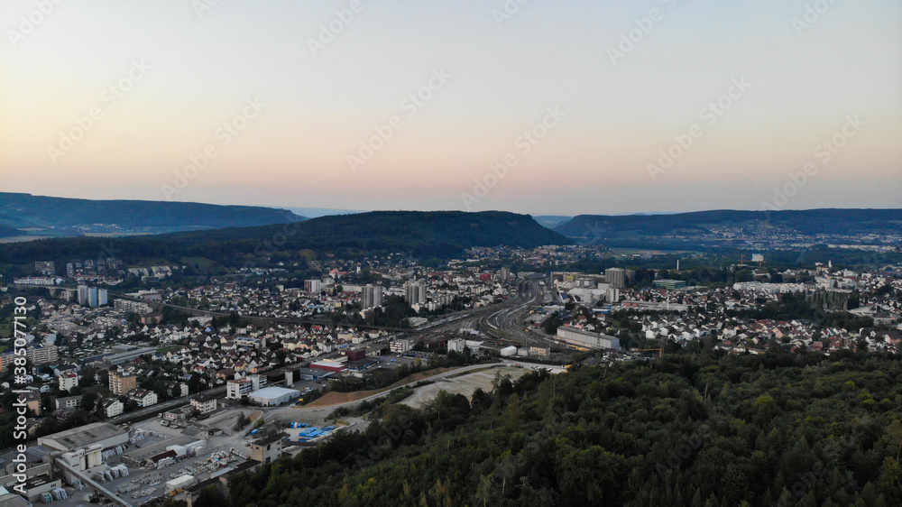Aerial view over Brugg after sunset. Industry, train station and residential area of Brugg, a village in canton aargau. Seen from Habsburg forest. Windisch, 8. August 2020.