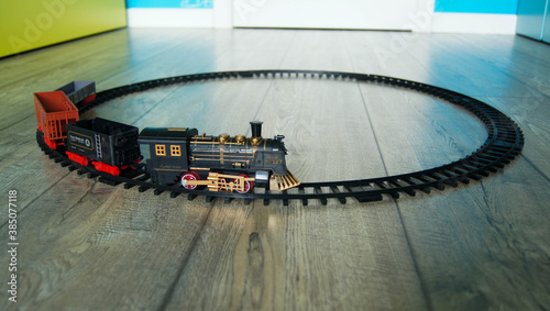 Closeup of a retro toy train on the circular track on the floor 