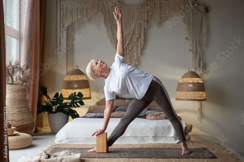 Senior woman practicing yoga, stretching in Utthita Trikonasana exercise, extended triangle pose photo