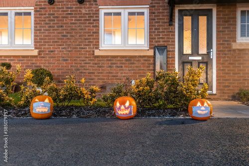 Halloween pumpkins wearing a face mask against coronavirus in front of a home entrance - Halloween theme during covid 19 pandemic - Culture and lifestyle