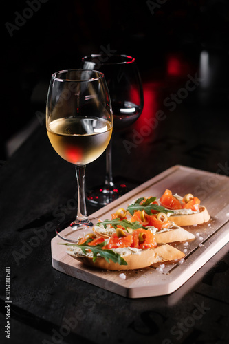 Set of snacks and glasses of wine. Bruschetta with cheese and salmon on a wooden board, served with red wine.