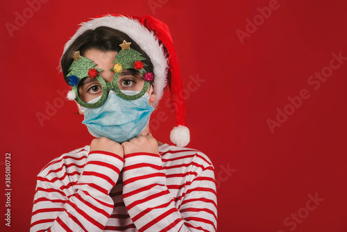 Merry Christmas, kid with medical mask and funny christmas glasses