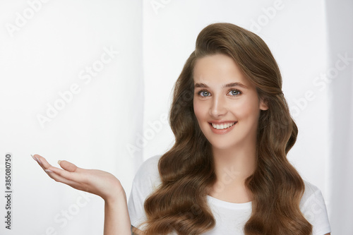 beautiful woman with long healthy curly hair holding arm for copy space