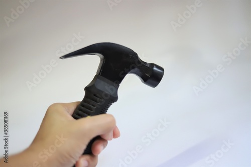 A brown hand holding a black hammer isolated on white background with text space