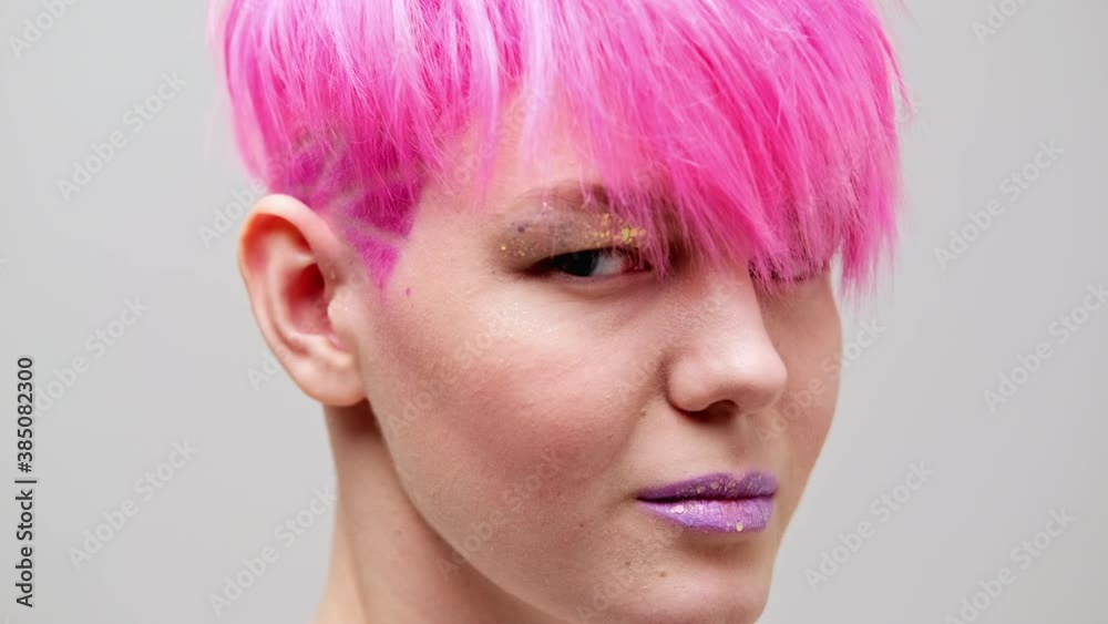 Young beautiful girl with a short haircut and pink hair. A homosexual lesbian model poses on a white background in the studio. Young beautiful girl with a short haircut and pink hair. A homosexual lesbian model poses on a white background in the studio.