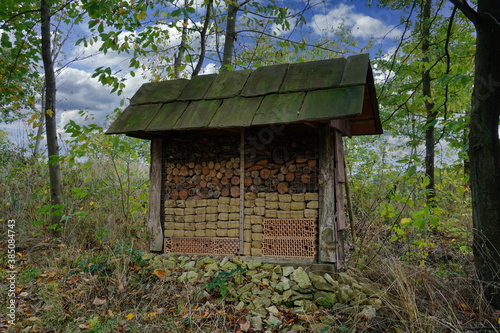 Ein großes Insektenhotel an einem Feldrand mit Dachziegeln, Holz und Backsteinen
