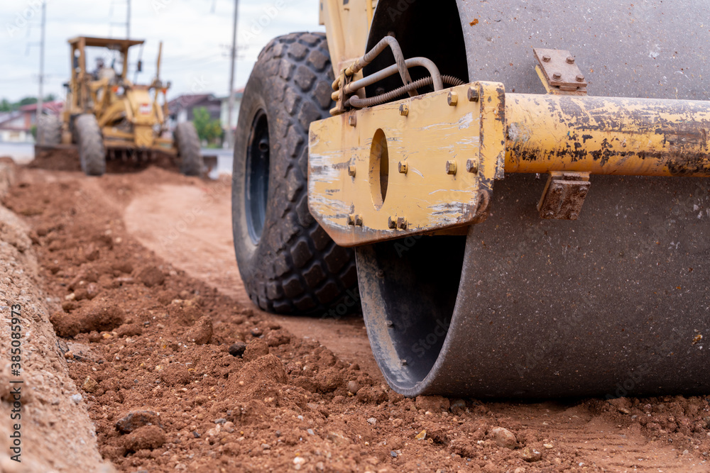 Close up Yellow vibratory soil and Motor Grader Civil compactor working on road construction site, Yellow vibratory soil compactor in road construction site Close up Yellow vibratory soil and Motor Grader Civil compactor working on road construction site, Yellow vibratory soil compactor in road construction site