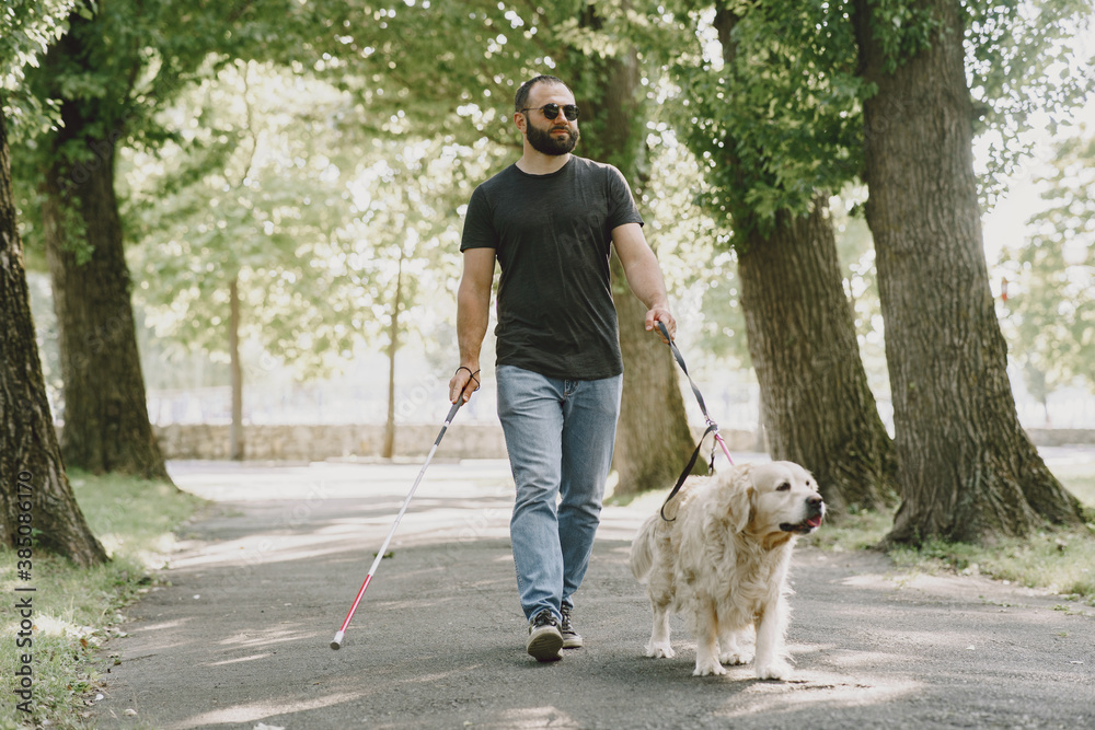 Guide dog helping blind man in the city. Handsome blind guy have rest with golden retriever in the city. Guide dog helping blind man in the city. Handsome blind guy have rest with golden retriever in the city.