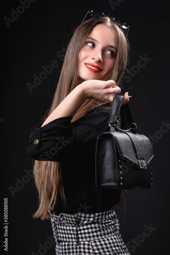Beautiful woman with handbag on black background