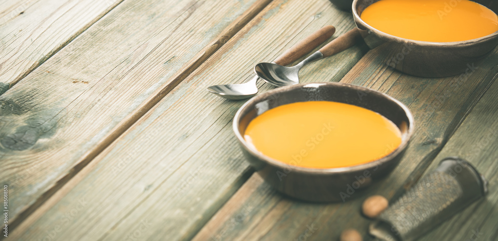 Pumpkin soup in bowls on wooden table, space for text Pumpkin soup in bowls on wooden table, space for text