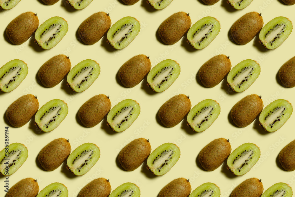 Kiwi pattern. Repetition of kiwi halves on a light yellow background. Top view of green and brown kiwi halves on a light surface. Horizontal. The concept of healthy food and vegetarianism. Kiwi pattern. Repetition of kiwi halves on a light yellow background. Top view of green and brown kiwi halves on a light surface. Horizontal. The concept of healthy food and vegetarianism.