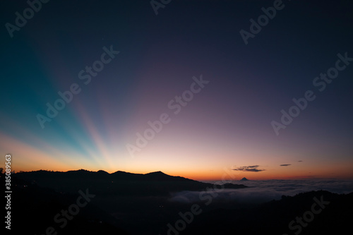 View of a colorful sunrise, where you can see a layer of clouds and some rays of sun
