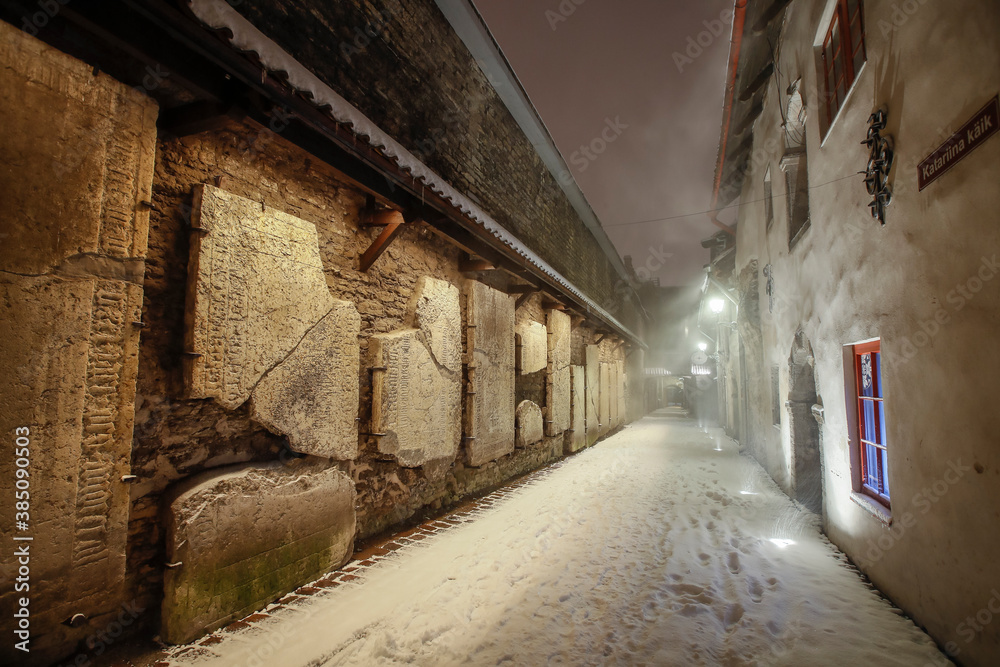 Obraz premium The st Catherine's passage - one of the most picturesque lanes of Old Tallinn and UNESCO cultural heritage site at the heavy winter snowfall night