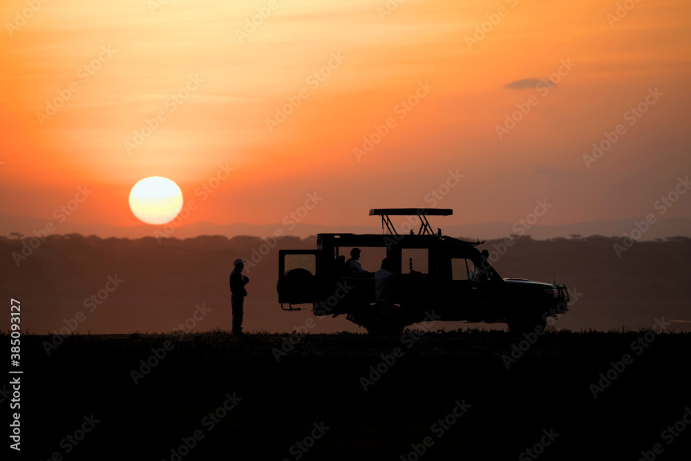 Fototapeta premium African safari car in red dawn sunrise with unknown silhouettes