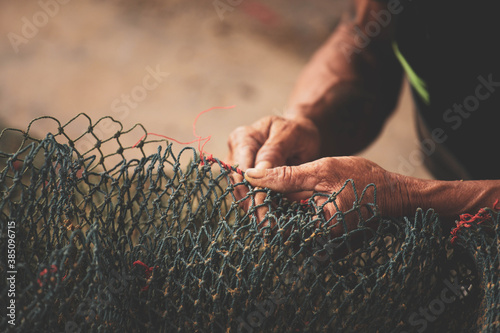 Selective focus on fisherman's hand, repairing fishing net photo