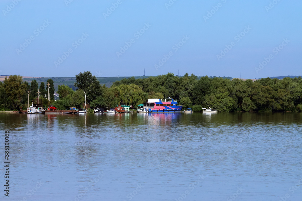 Barcos de distintos tipos atracados en la orilla del río Danubio. Barcos tradicionales y barcos de pasajero en la orilla del ramal de San Jorge en el delta del Danubio a la altura de Nufaru, Rumanía. Barcos de distintos tipos atracados en la orilla del río Danubio. Barcos tradicionales y barcos de pasajero en la orilla del ramal de San Jorge en el delta del Danubio a la altura de Nufaru, Rumanía.