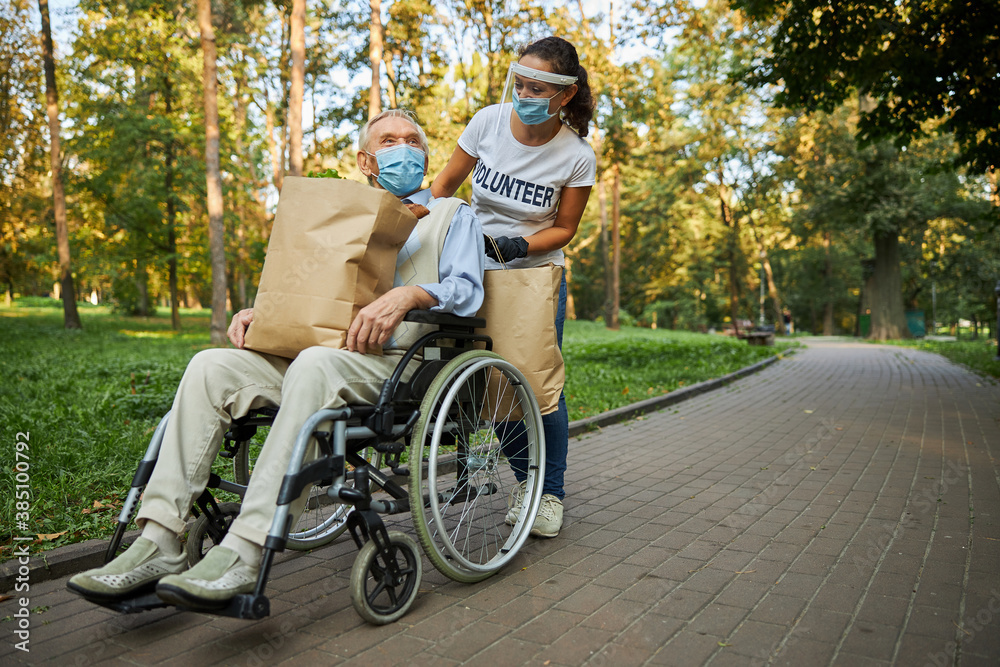 Female volunteer helping to the mature disabled man Female volunteer helping to the mature disabled man