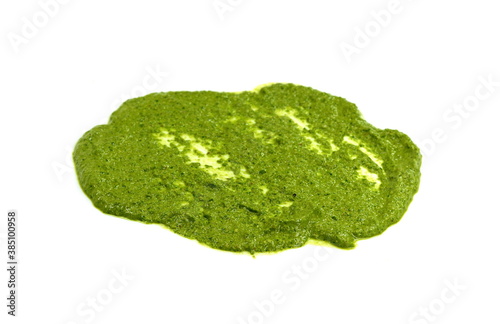Pesto spread or blob in a bowl isolated on white background. Green italian homemade spilled sauce made of ground basil, garlic, pine seeds, olives and pecorino sardo cheese 