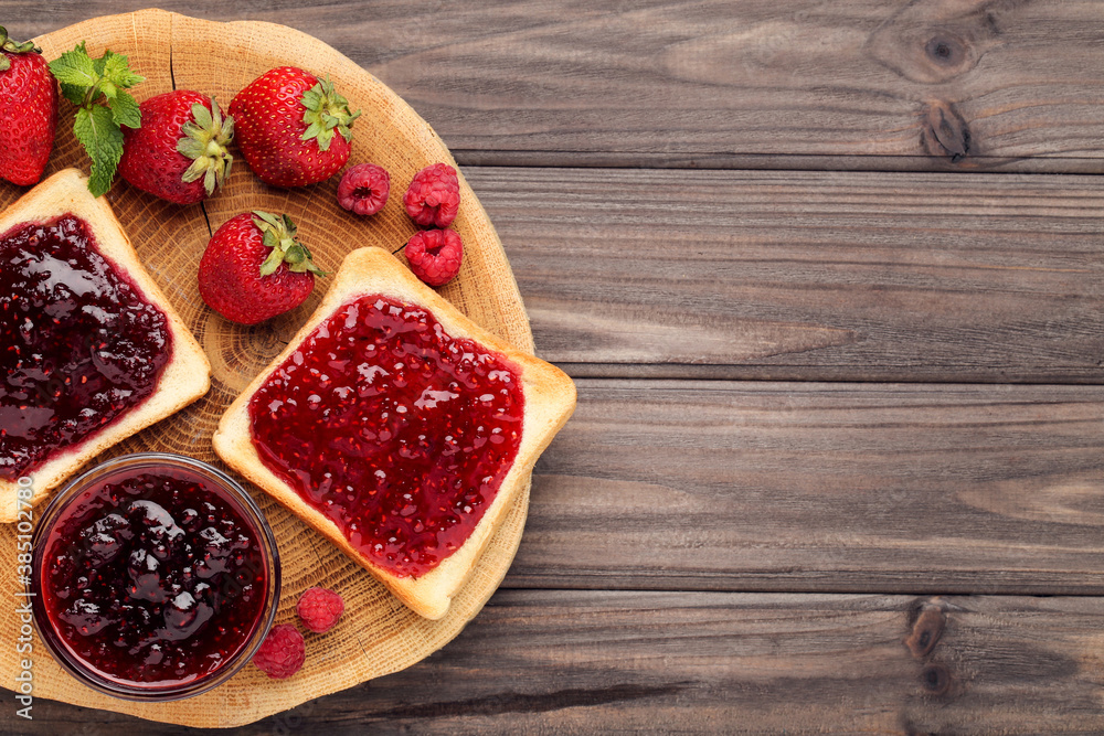 Toasts with jam and ripe berries on wooden table Toasts with jam and ripe berries on wooden table