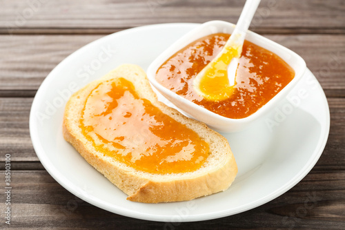 Toast with apricot jam in bowl on wooden table