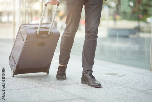 Cropped shot of a businessman pulling his suitcase outside the airport