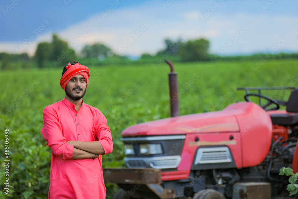 Technology and people concept, Portrait of young indian farmer with tractor Technology and people concept, Portrait of young indian farmer with tractor