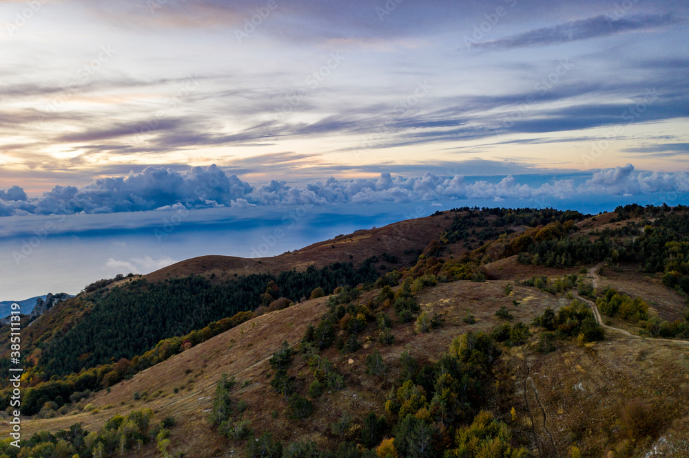 Fototapeta premium panoramic view of yellow autumn mountains against a background of blue haze and storm clouds filmed from a drone