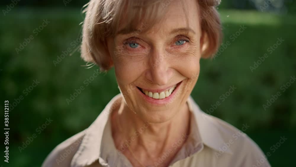 Mature woman looking at camera. Senior lady smiling in green park