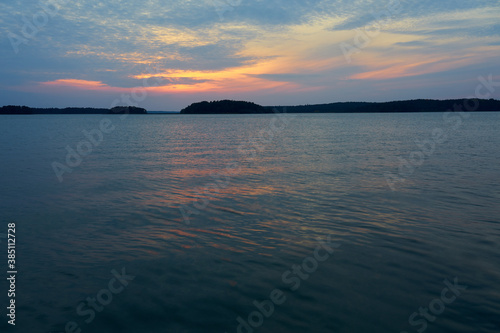 Colorful cloudy sky on a sunset over the sea with horizon on a background and reflection on water.