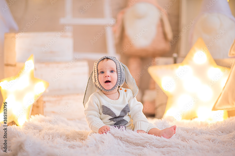 Fototapeta premium Baby boy in Christmas suit like a rabbit posing in a room with Christmas decor.