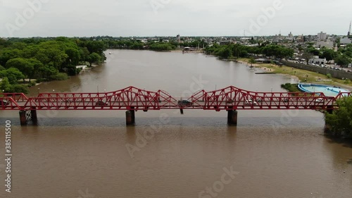 Video aéreo del río y las márgenes del río que circula por la ciudad y un puente rojo construido de metal remachado. photo