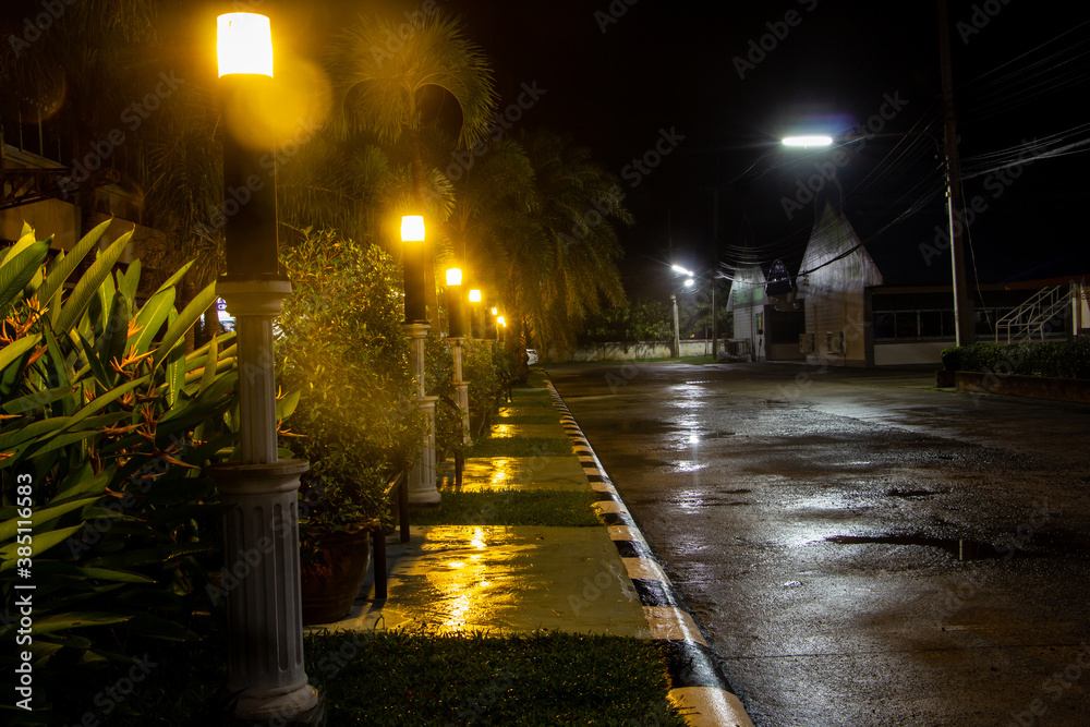 Pavement with road beside at night. And yellow light lantern illuminate the ground.