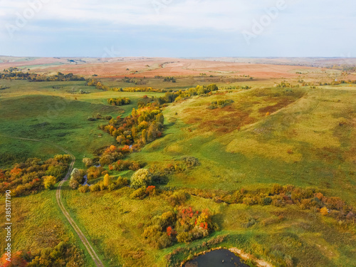 Aerial view of the autumn landscape with hills and bright yellow colors of falling leaves. Drone shooting of scenic autumn backgrounds. © Irina