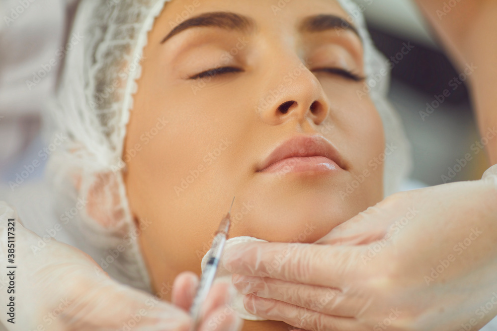 therapists hands in gloves with syringe and cotton pad making botox filler injection in womans underlip therapists hands in gloves with syringe and cotton pad making botox filler injection in womans underlip
