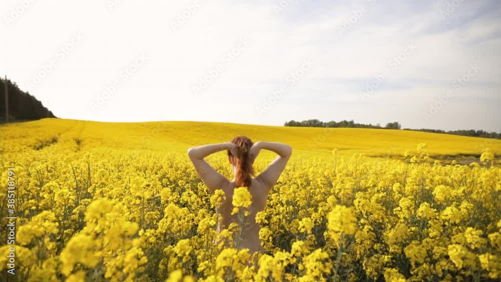 Cute naturist woman enjoys Spring in rapeseed field without ... 