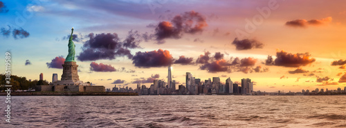 Panoramic view of the Statue of Liberty and Downtown Manhattan in the background. Dramatic Colorful Sunrise Artistic Render. Taken in Jersey City, New Jersey, United States.