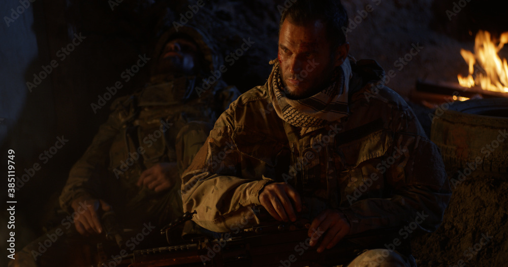 Soldier resting near fire at night