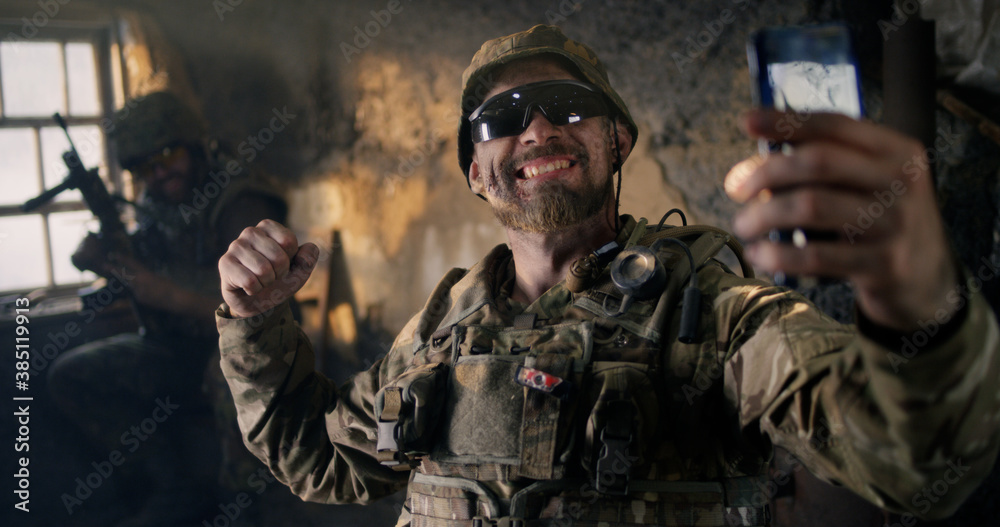 Fototapeta premium Military man using smartphone inside grungy building