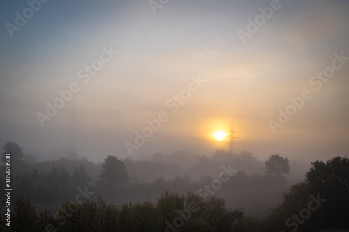  foggy landscape with a big power pole in the sunrise